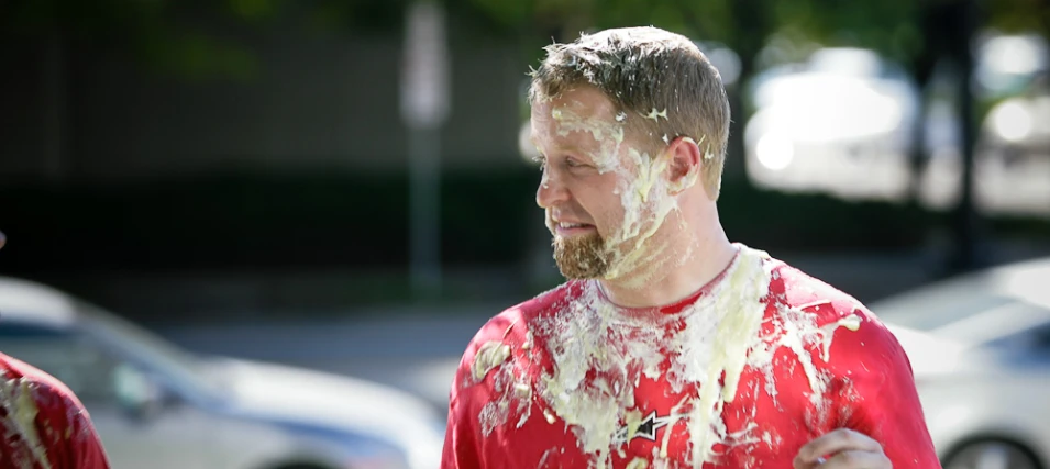 man covered with paint and sprinkled on face with another man in the background