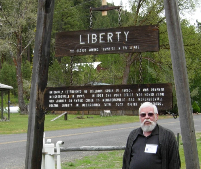 an old man posing for a picture in front of a sign