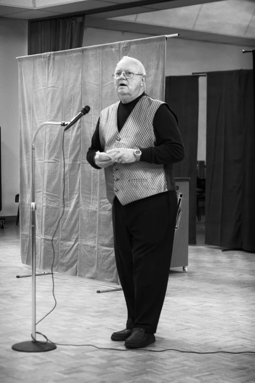 an older man standing in front of a microphone