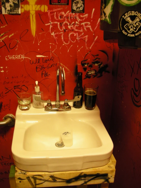 the bathroom has a white sink with graffiti on it