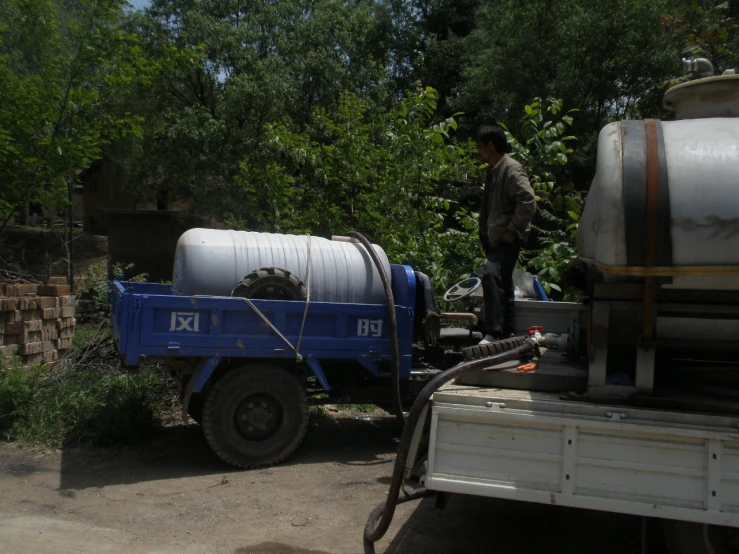 a man standing near two gas tanks on the back of a truck