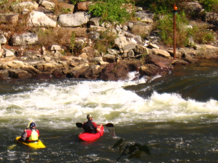 two people in kayaks paddling down a raging river