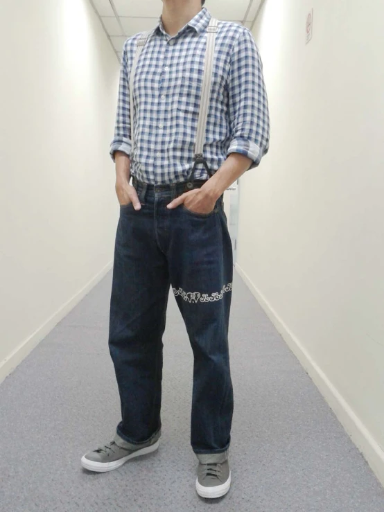 a man wearing glasses and suspenders with a large piece of luggage