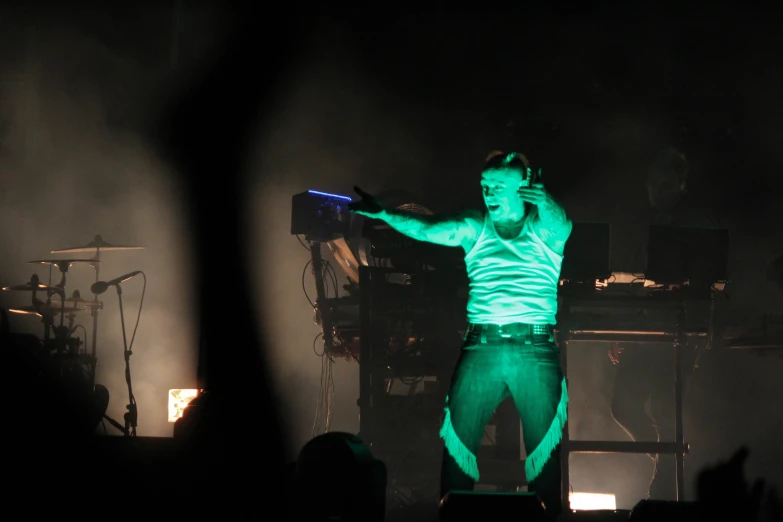 a man in green lighting standing on a stage