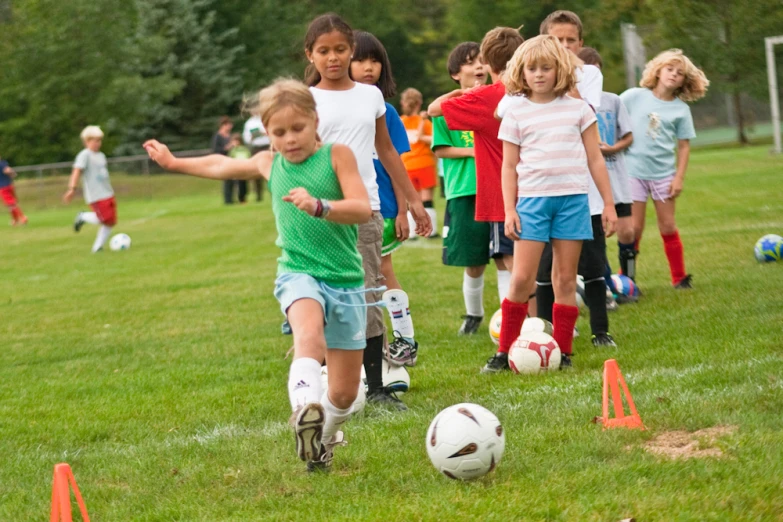 children play soccer in a field next to cones