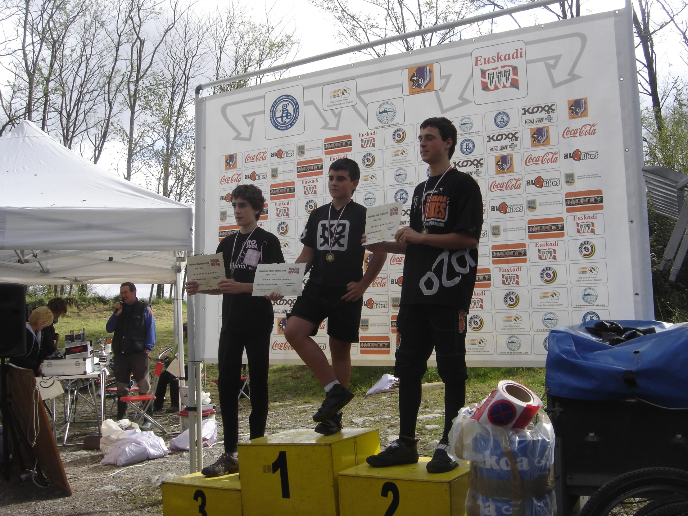 four s on podiums smiling while one boy holds his number