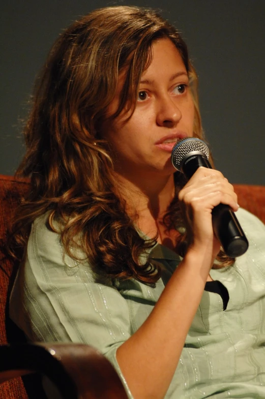 a woman is sitting in a chair holding a microphone