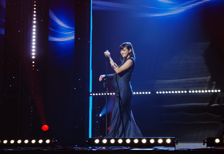 a woman in a blue dress holds her microphone