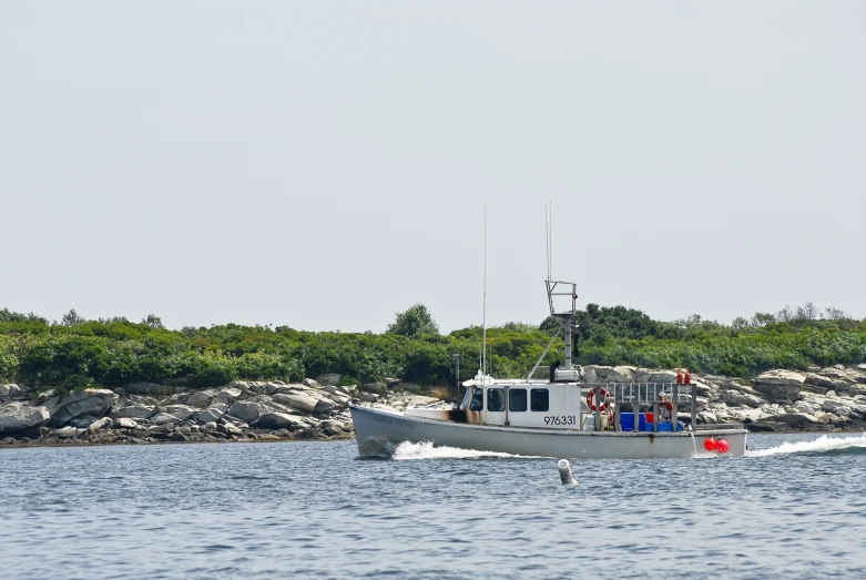 a boat sailing along the water near a shoreline