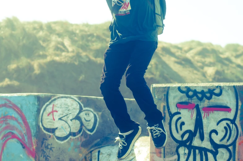 a man doing skateboard tricks near wall with graffiti