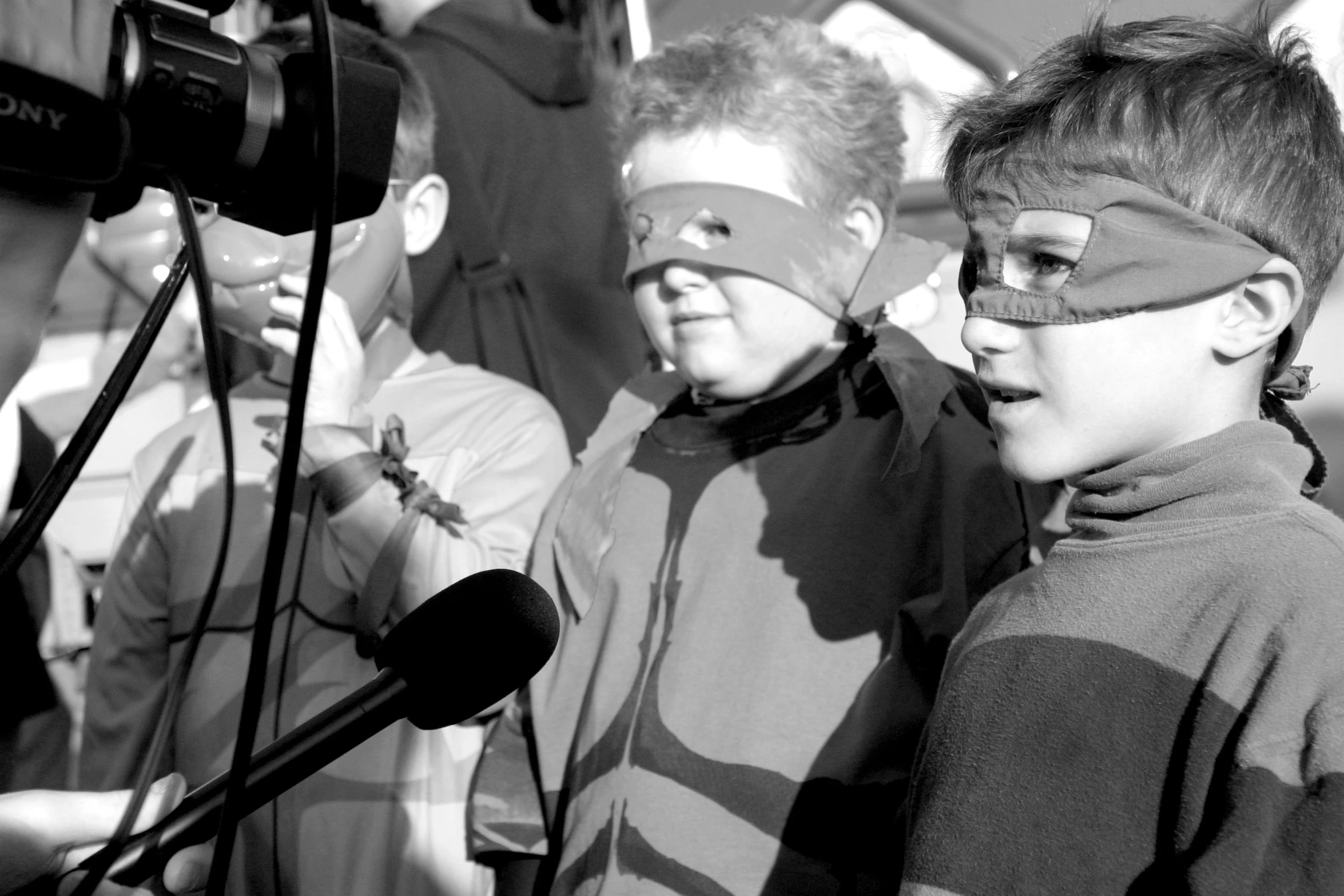 two boys wearing blindfolds and staring into a microphone