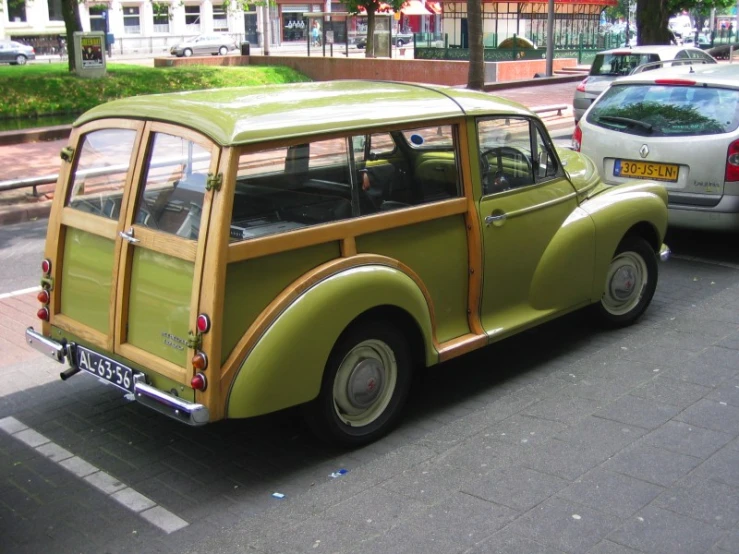 a small green and wooden car sitting next to a white car