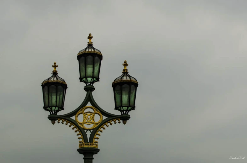 four lights on a pole are shown against a cloudy sky