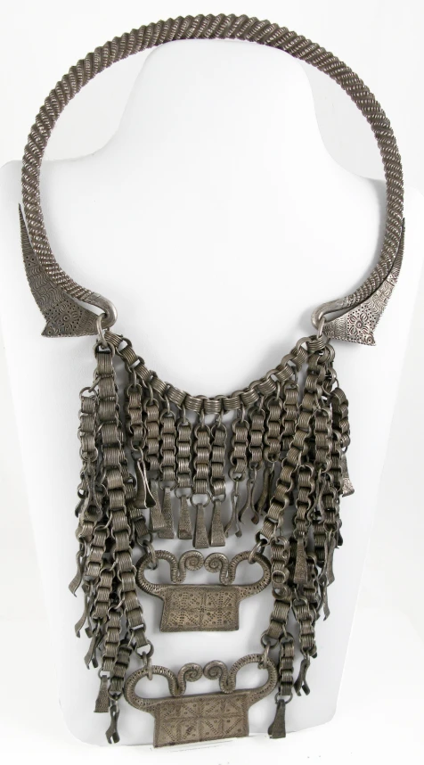 a silver metal necklace is displayed on a white display