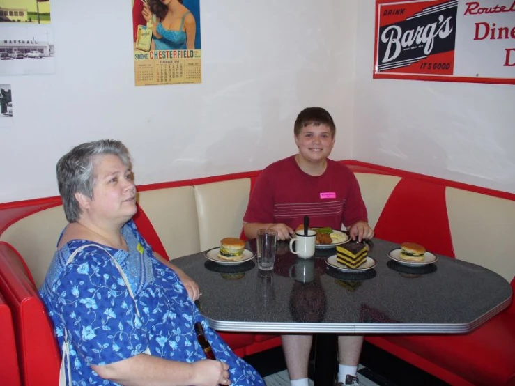 two women sitting at a table with plates of food