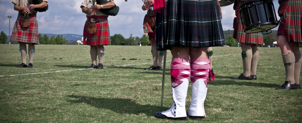 several men dressed in kilts are standing on a field
