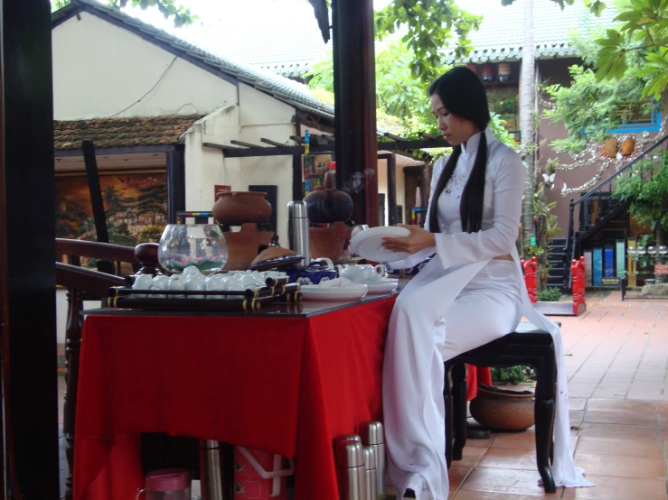 a woman in a white dress seated at a table with food