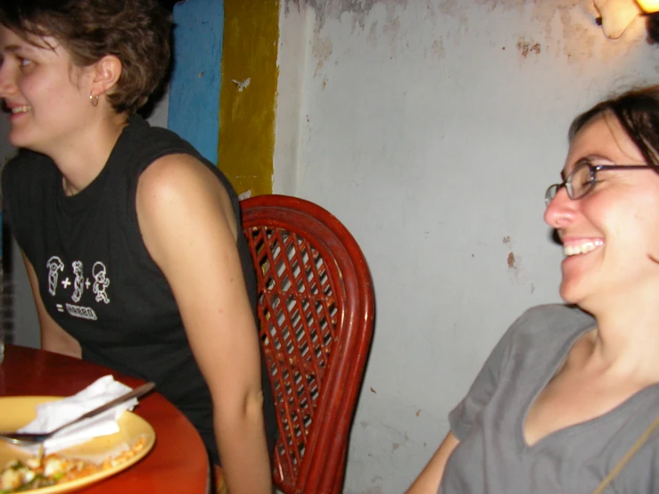 two woman sitting at a table and smiling