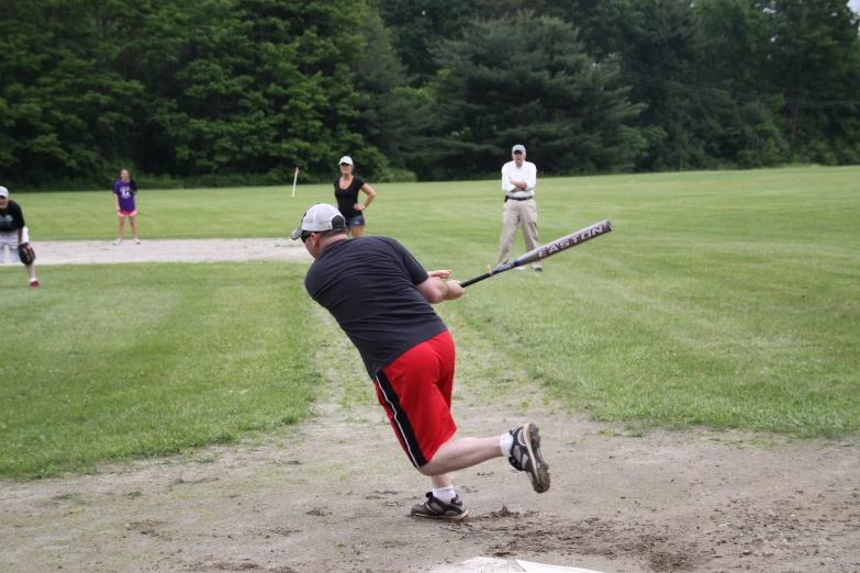 a man in a red shorts hits a baseball with a bat