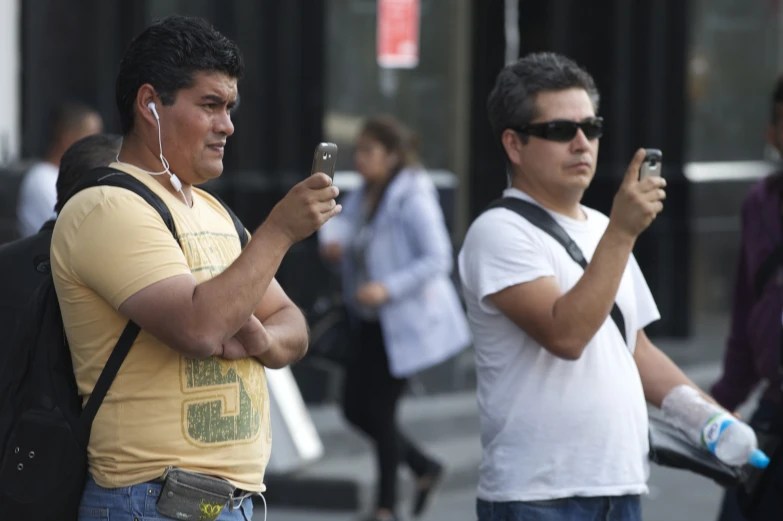 there are three men standing in the street and one man is holding a camera