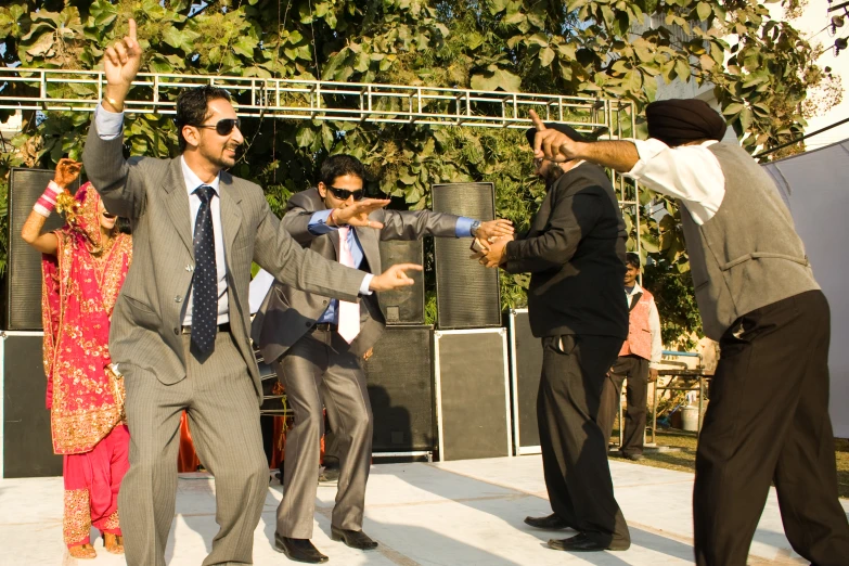 people dance in suits and ties as other people hold their arms up