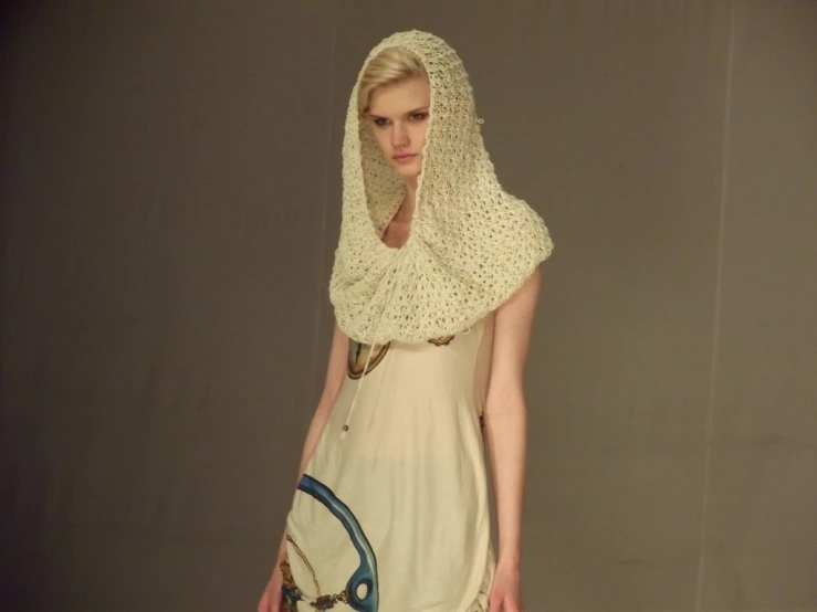 a model wears an embellished veil while walking down the catwalk