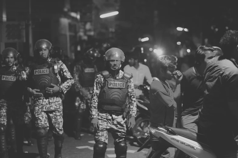 the police in the uniform of a motorcycle cop standing beside some people on the street