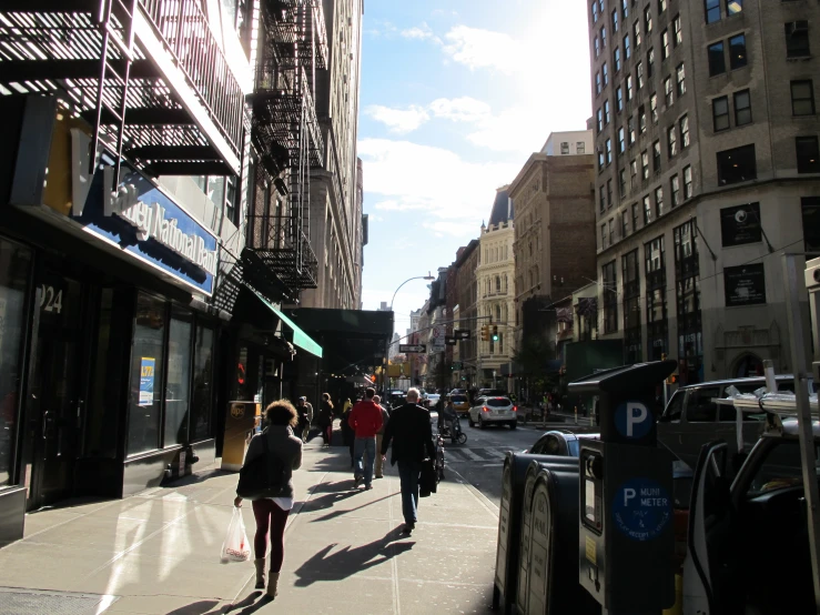 people walking down a street between tall buildings