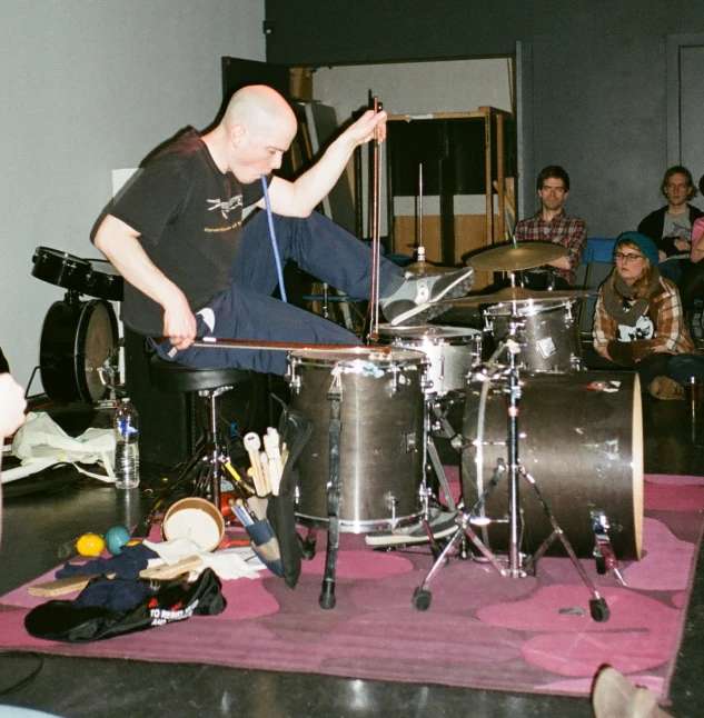 a man on drums with people seated in the background