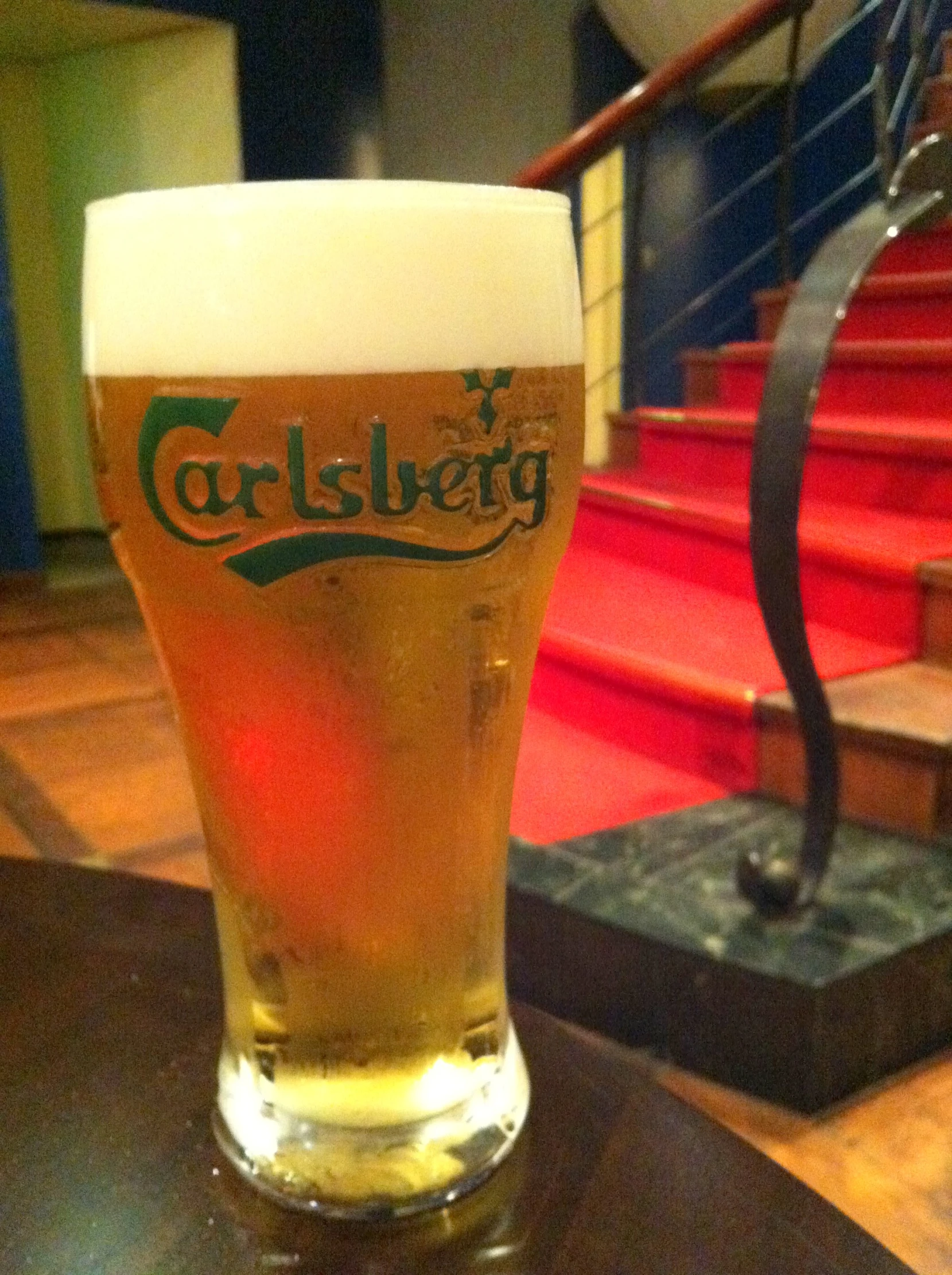 a glass of beer sitting on a table in front of stairs