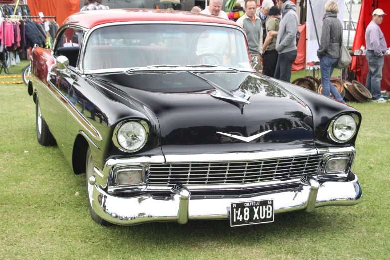 an old, classic black car sits in a grass field at a car show