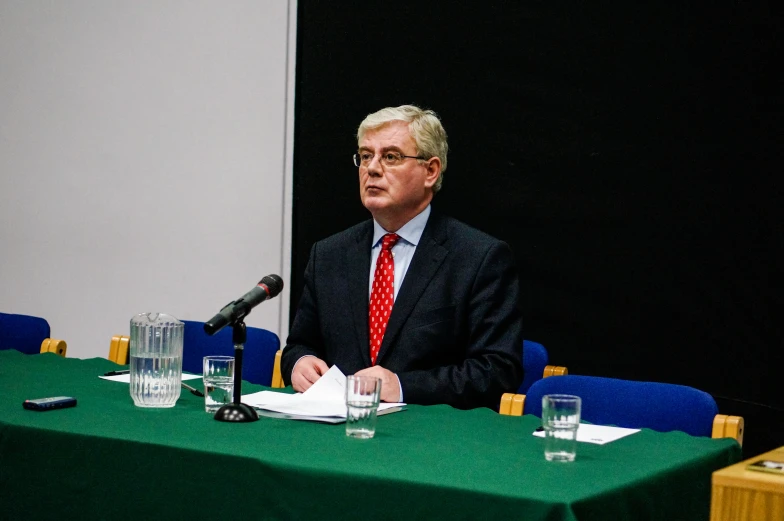 a man in a business suit sitting at a table with water glasses