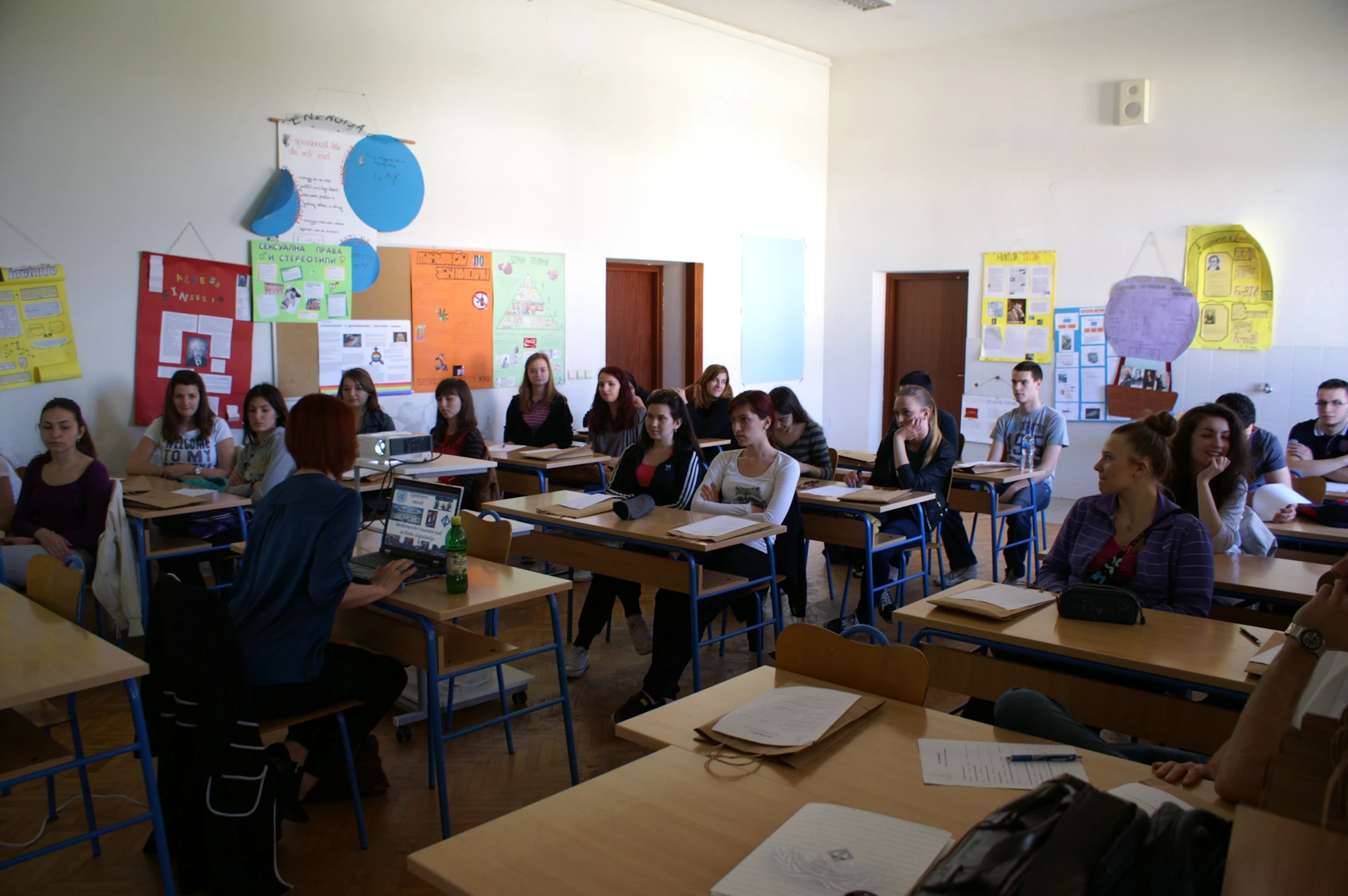 the students are sitting at desks and making notes