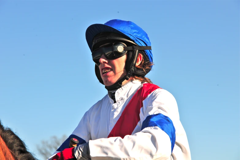 a jockey is dressed in white and blue and riding on his horse