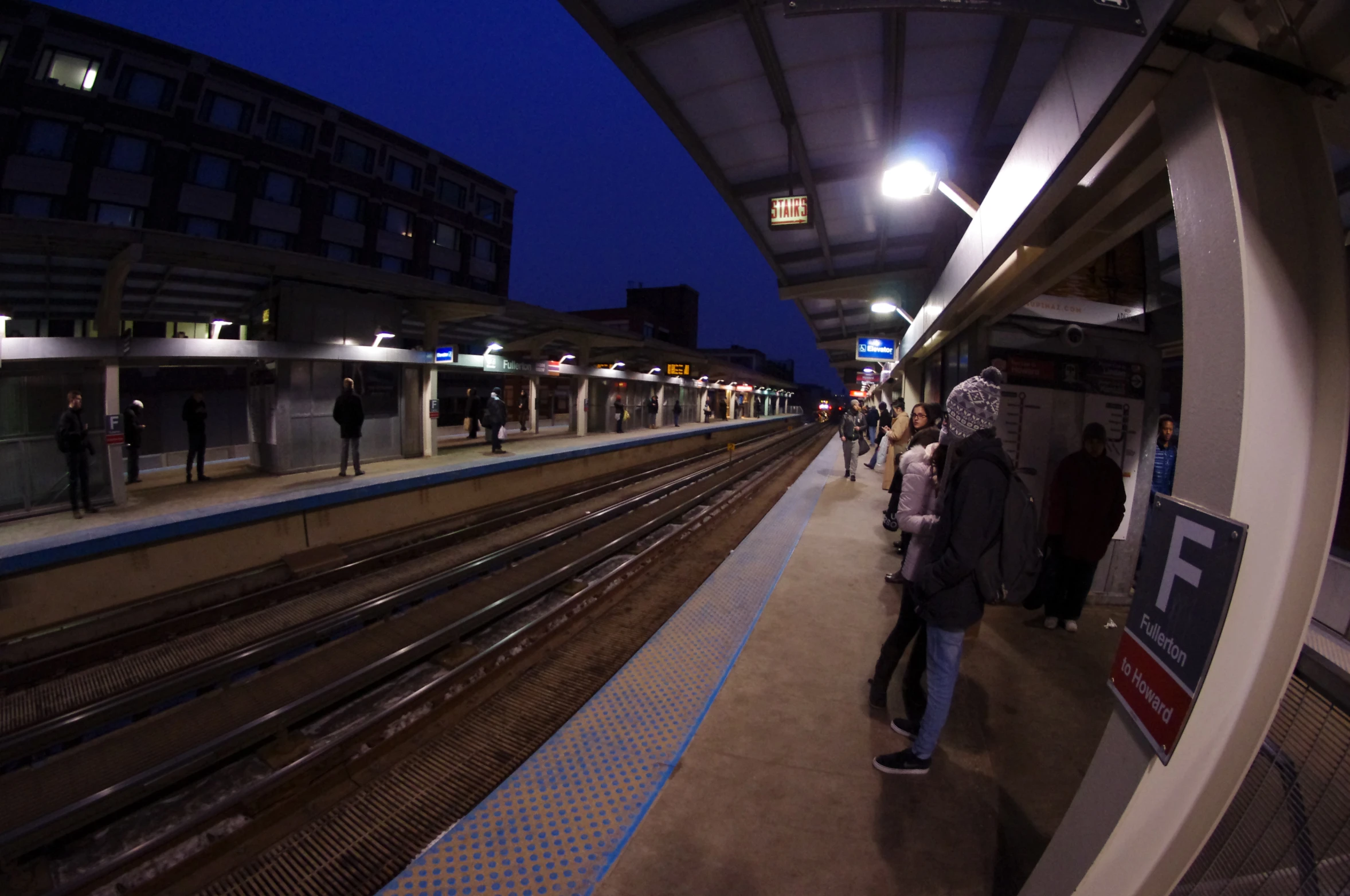 people are standing on a platform near the tracks