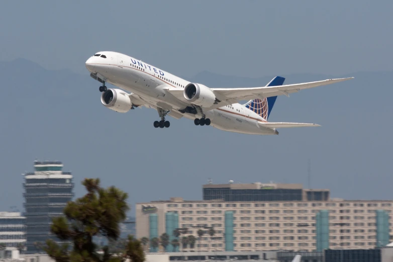 an airplane flying with it's landing gear down in front of the city