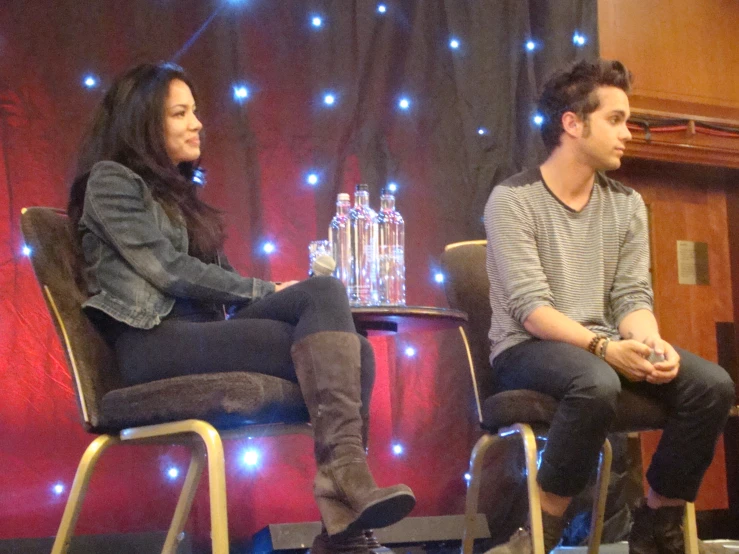 the two people are sitting on chairs in a stage setting