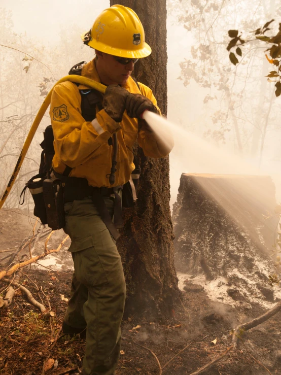 the firefighter is using the hose to extinguish the water out of the ground