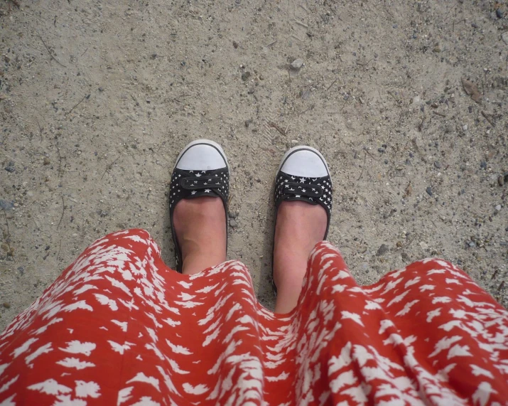 a person wearing patterned shoes standing in a concrete surface