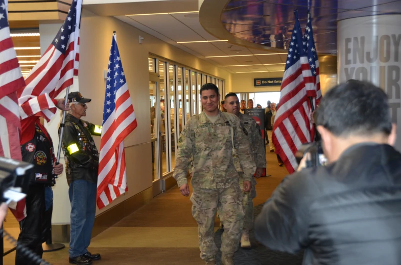 a few men walk down a hallway holding american flags