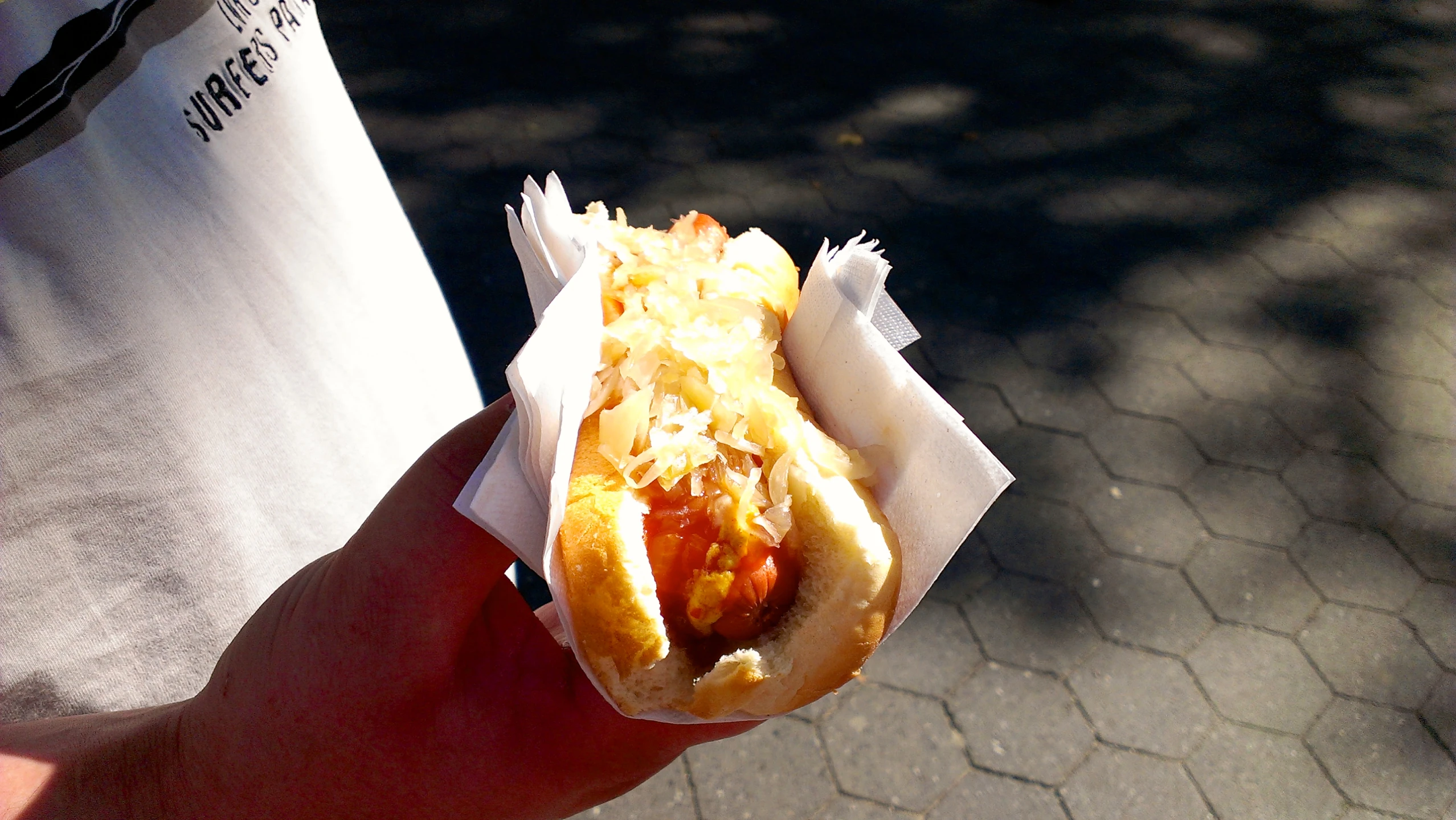 a hand holding up a dog with ketchup and relish