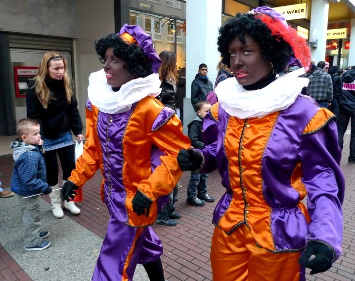 two women dressed in bright costumes and one woman standing on the street