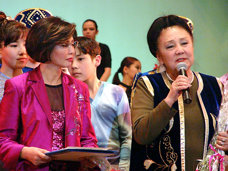 a woman holding a microphone while speaking into it