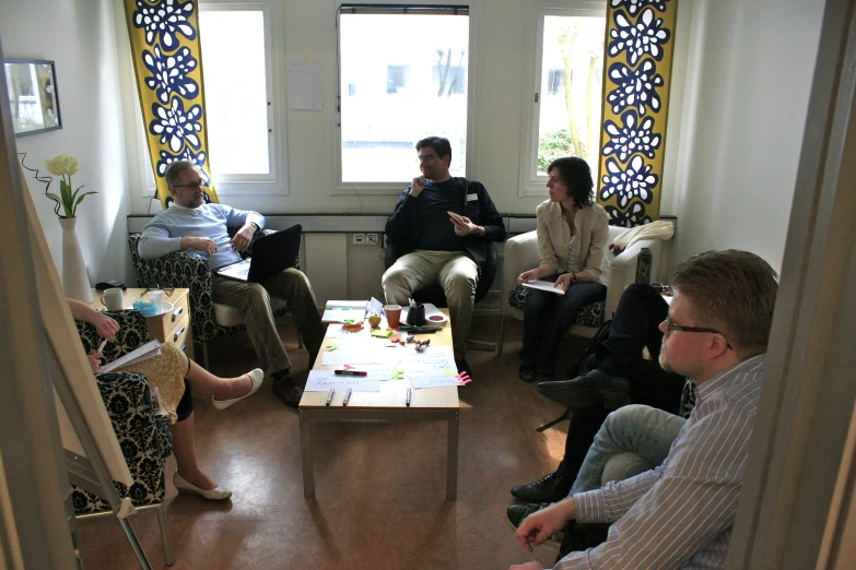 five people in a small living room and one man holding a sign