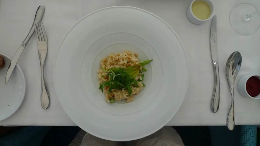 a large meal of rice and greens in a bowl on a white table