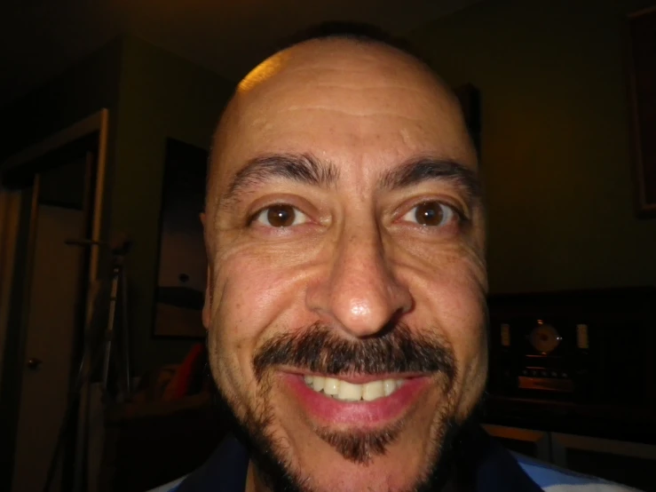 an old man with a goatee smiles at the camera