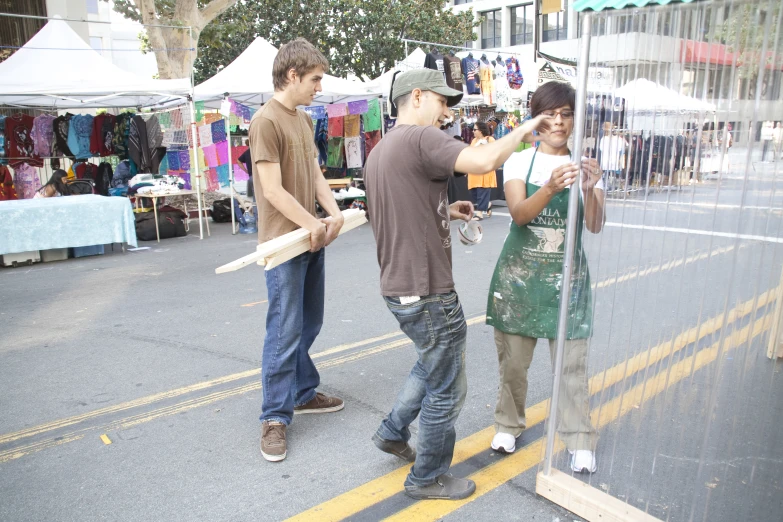 two young men stand outside a market and look at their cell phone