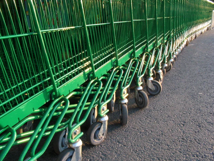 several green shopping carts parked next to each other on the street