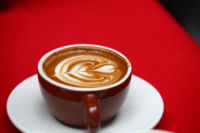 an espresso sits on a white saucer on a red counter