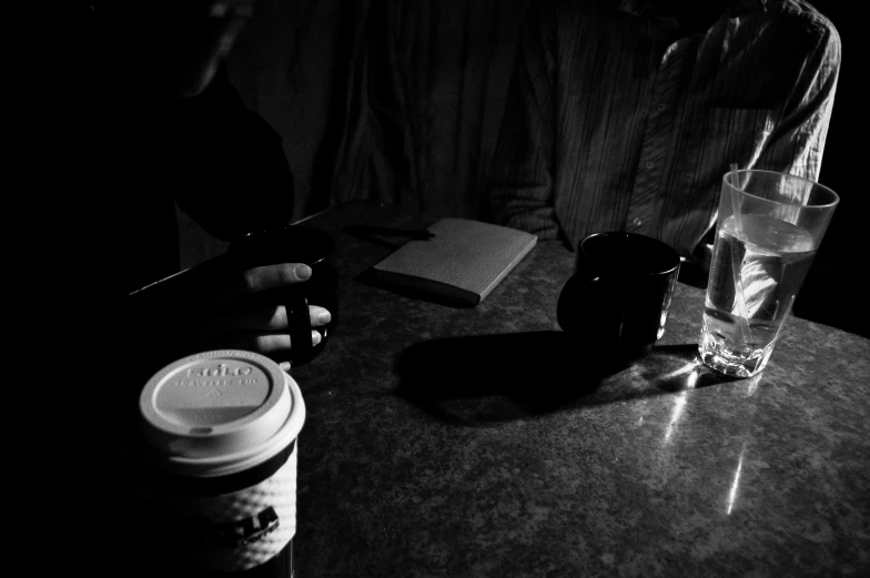 person at table with a mug and a notebook on it